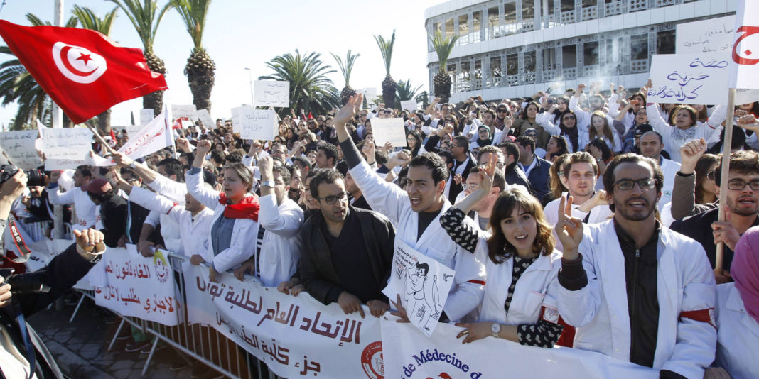 Doctors and resident doctors shout slogans during a demonstration against the government's new draft law outside Constituent Assembly headquarters in Tunisia