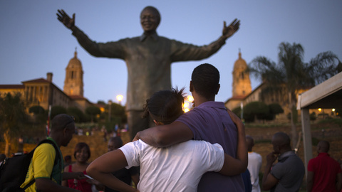 A couple stands near a bronze statue of late former South African President Nelson Mandela hours after it was unveiled as part of Day of Reconciliation celebrations at the Union Buildings in Pretoria